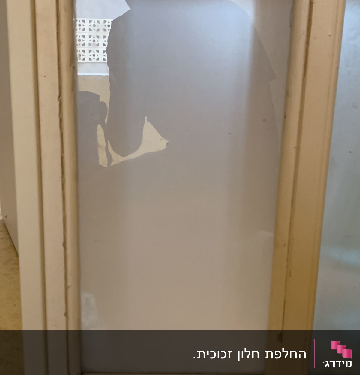 צללית אדם מאחורי זכוכית חלבית במסגרת עץ